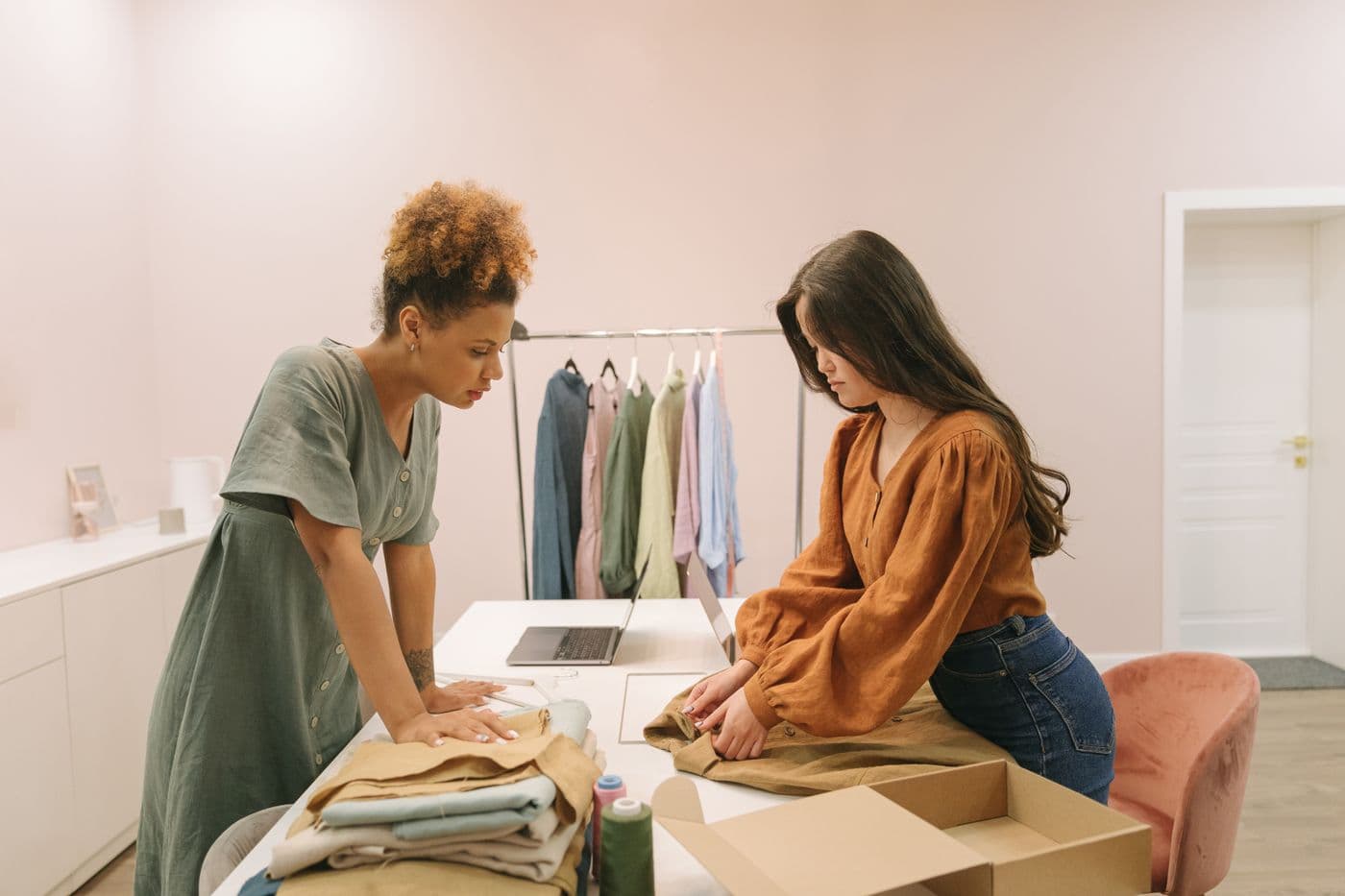 Two people preparing garments together in a small clothing studio