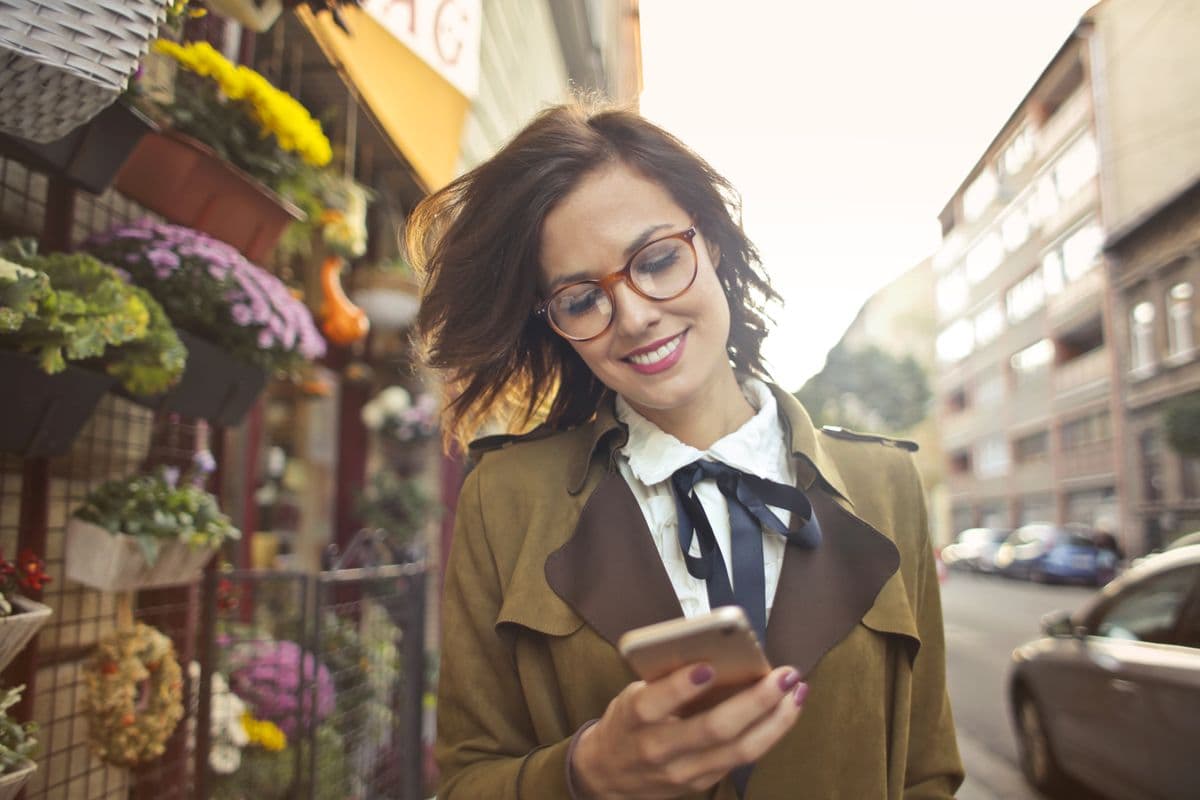 A woman reading her phone outside a flower shop