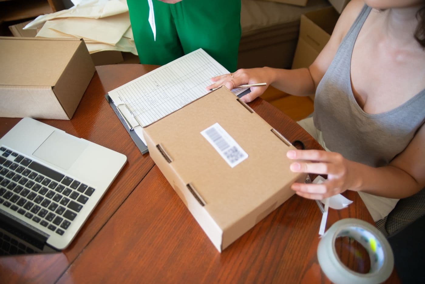 An online shop preparing a parcel beside a laptop and order book