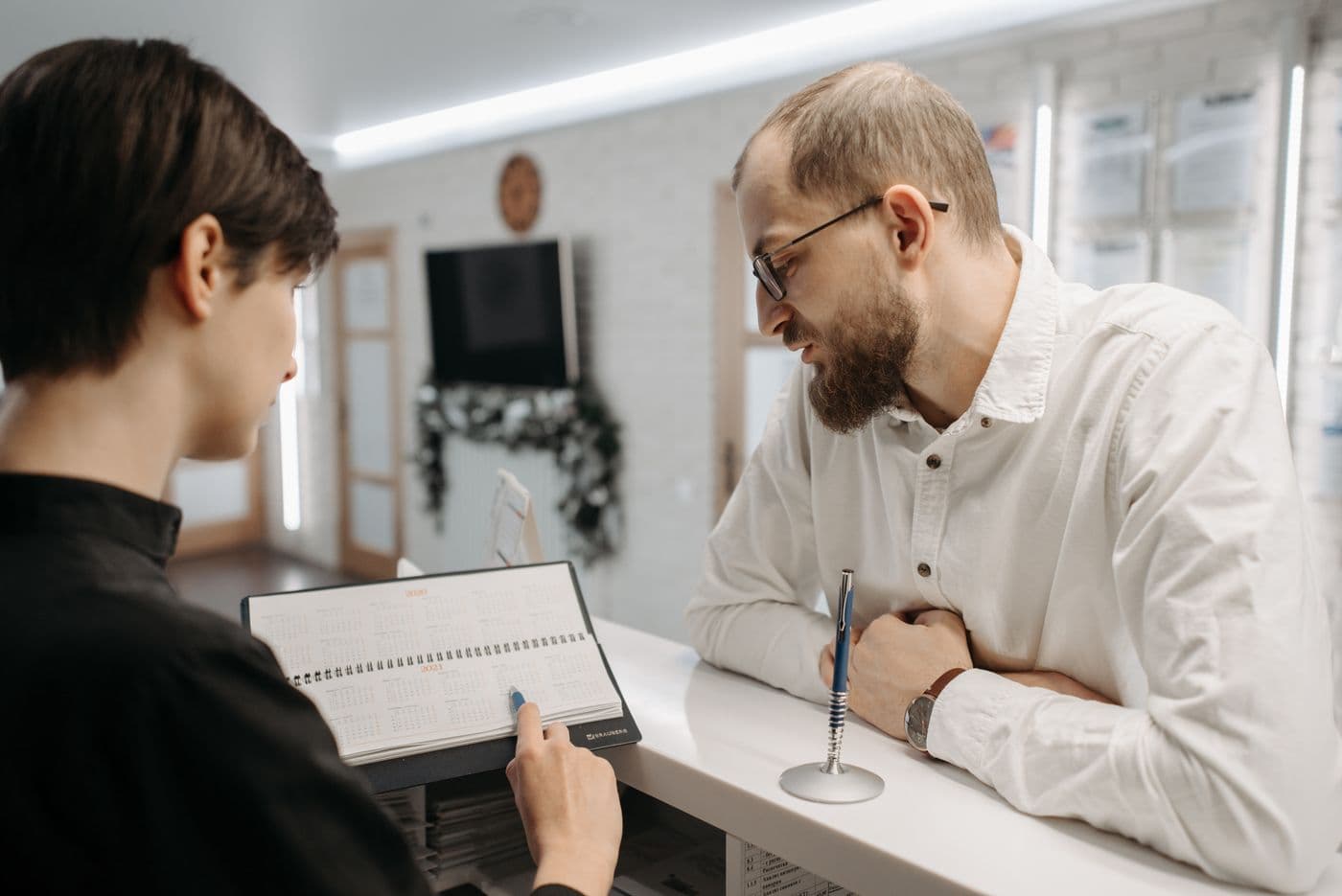 A receptionist and client reviewing an appointment calendar together
